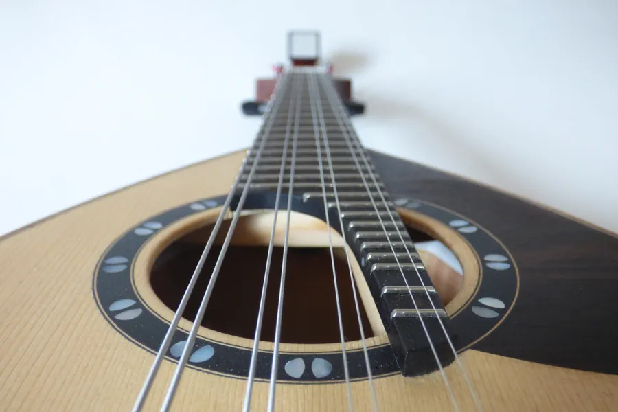 Dettaglio di un mandolino classico artigianale con corde e rosetta intarsiata sulla tavola in legno